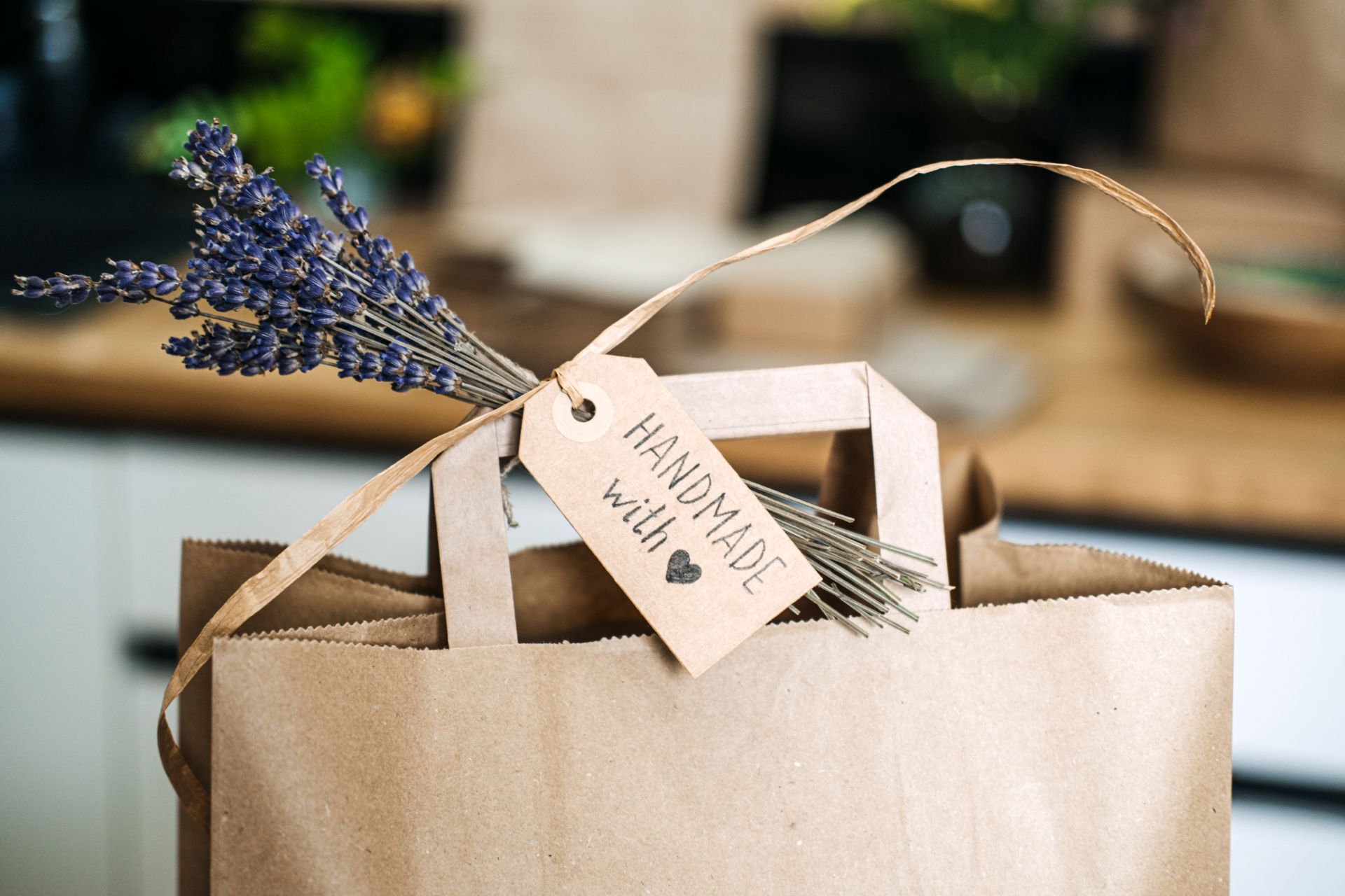 Papieretikett mit der Aufschrift Handmade with Love an einer braunen Tuete mit Lavendel – Beispiel fuer persoenliche Produktkennzeichnung im Einzelhandel
