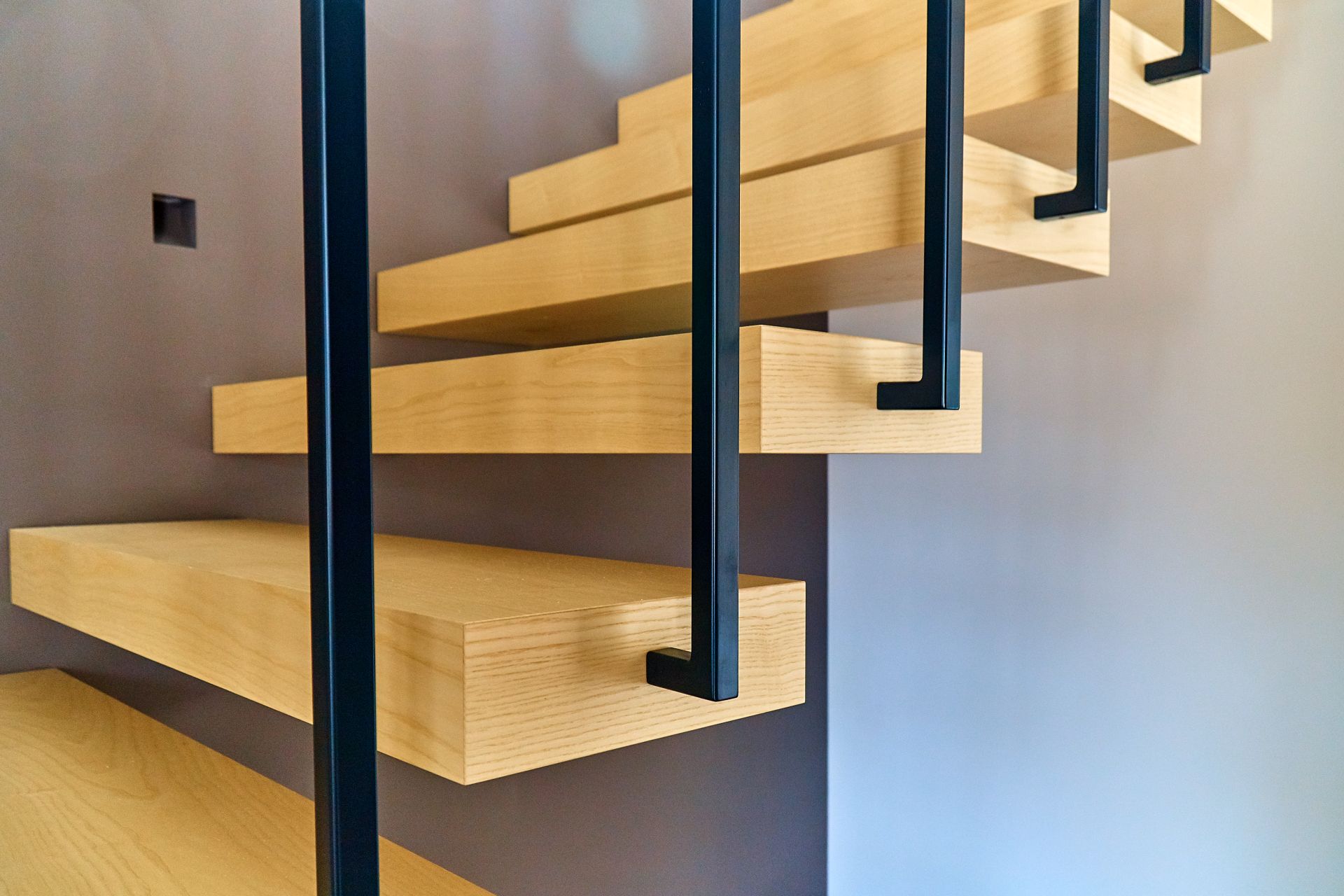 Detailaufnahme einer modernen Schwebetreppe aus Holz mit schwarzem Metallgeländer, elegante Lösung beim Treppen kaufen