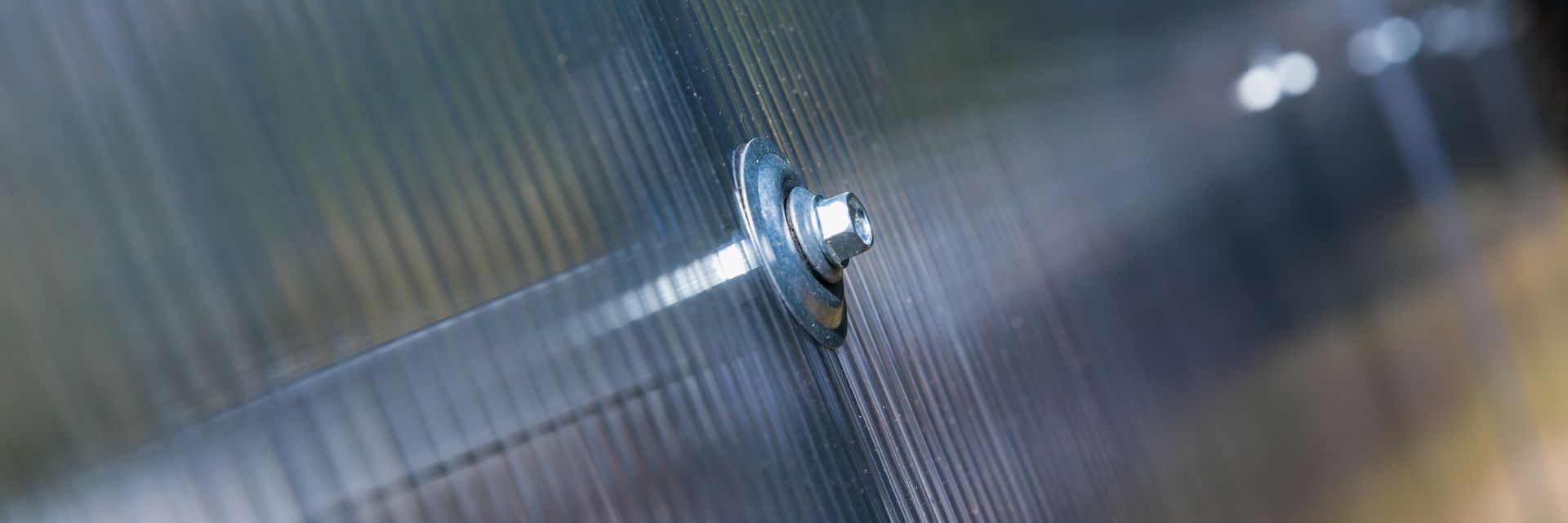 Nahaufnahme einer korrekt verschraubten Doppelstegplatte – zeigt sichere Montage mit Unterlegscheibe auf Polycarbonat