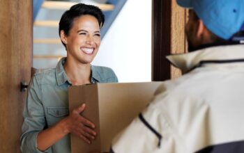 Frau nimmt Paket von Zusteller entgegen und lacht, sicherer Empfang dank Paketbriefkasten