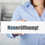 Hand hält Schild mit Neueröffnung | Blutentnahmestuhl