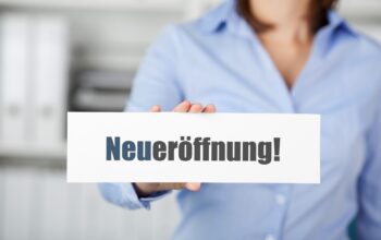 Hand hält Schild mit Neueröffnung | Blutentnahmestuhl