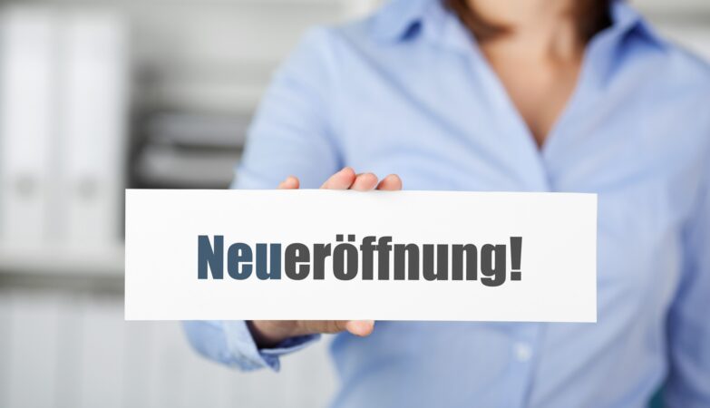Hand hält Schild mit Neueröffnung | Blutentnahmestuhl