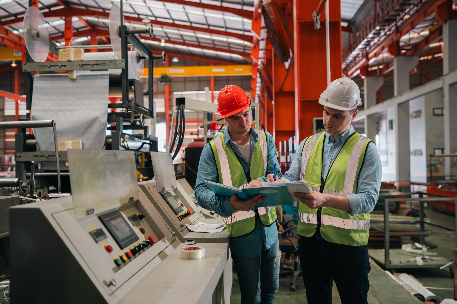 Zwei Ingenieure prüfen Produktionsunterlagen in Werkhalle | Entstauber