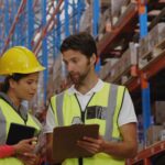 Mitarbeiter in Lagerhalle analysieren Prozesse und prüfen Flächenoptimierung für eine Lagerbühne