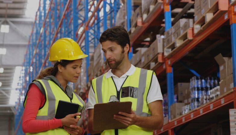 Mitarbeiter in Lagerhalle analysieren Prozesse und prüfen Flächenoptimierung für eine Lagerbühne